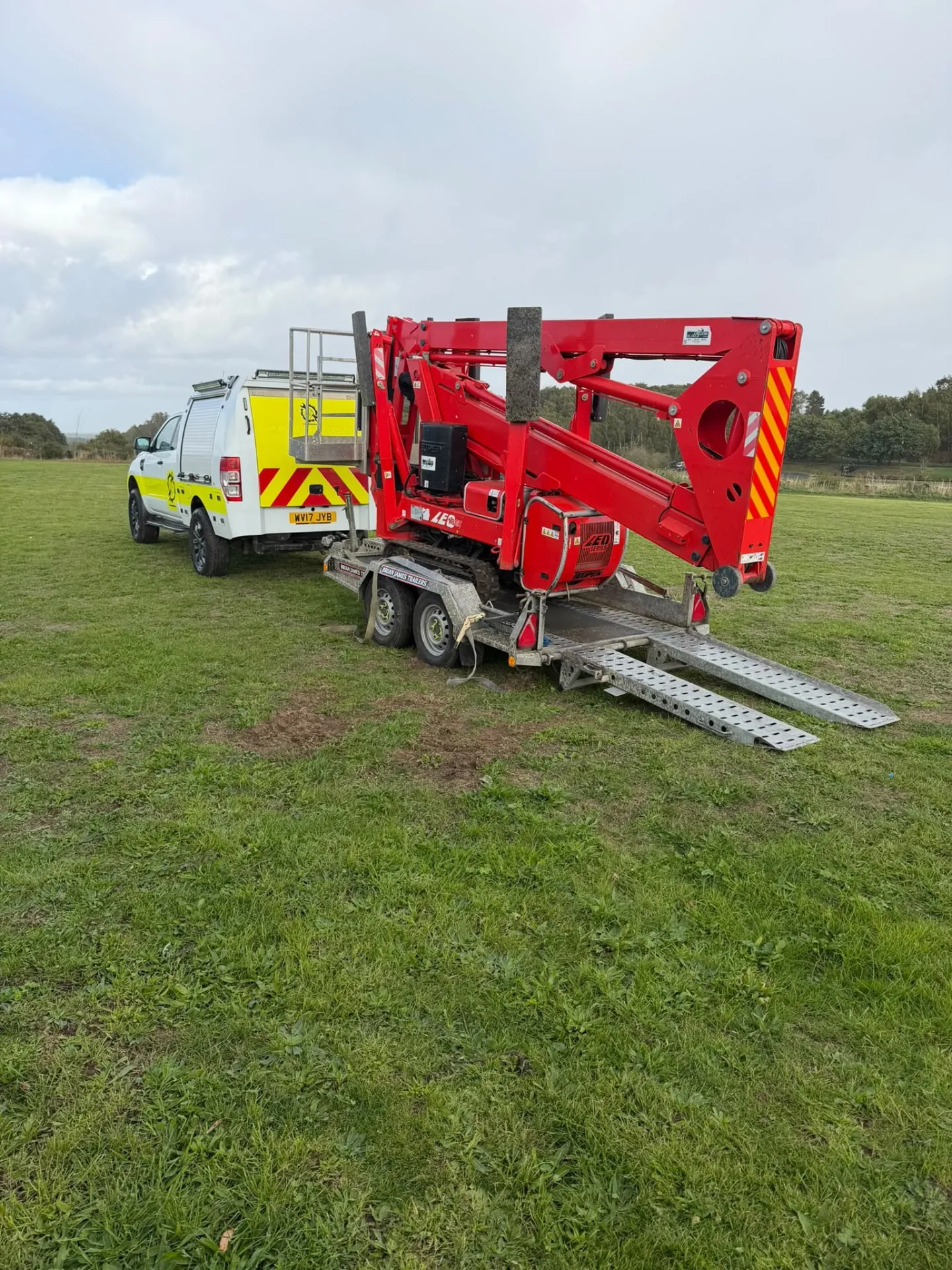 Teupen LEO 18 GT tracked cherry picker folded on its trailer behind the van, ready to travel to a job