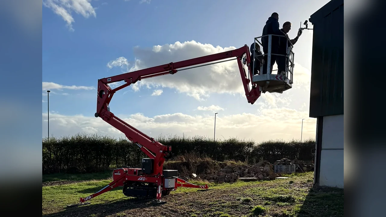 Two people in a cherry picker basket inspecting the eaves of a building
