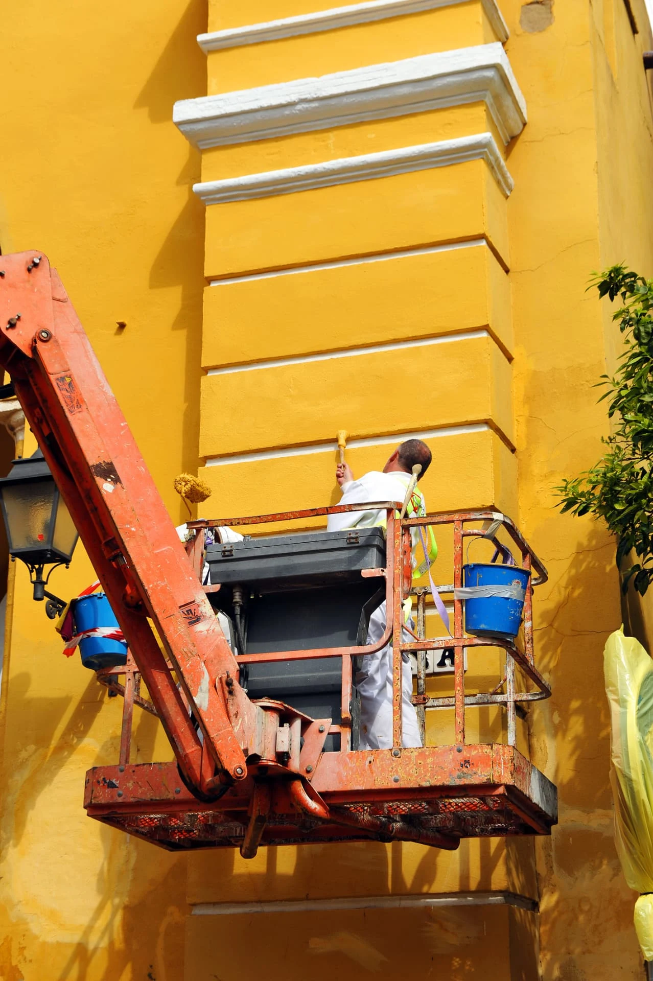 Painters on a raised access platform painting a building facade