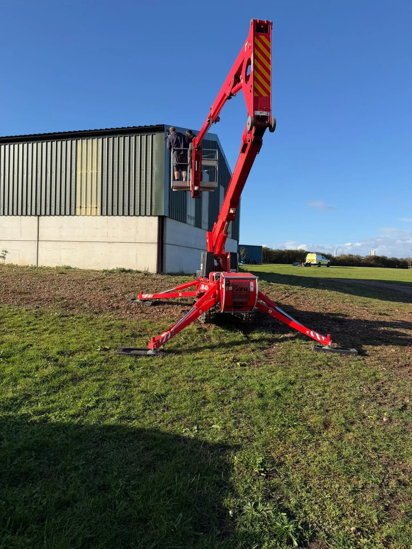 Tracked cherry picker raised to the roofline for roof repairs and maintenance